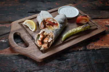 Yoğurtlu tavuk kebabı dürümü ve ahşap arka planda izole edilmiş acı biber.