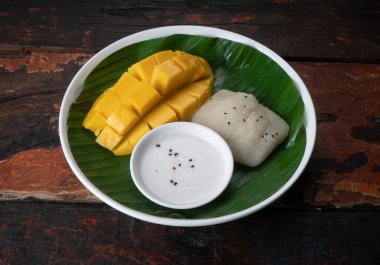 Manzaralı Tayland tatlı mangosu muz yaprağının üzerinde yapışkan pirinç kırsal ahşap masada yalıtılmış.