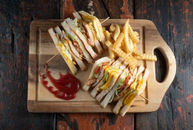 Tavuklu sandviç ve patates kızartması manzarası kırsal ahşap masada izole edilmiş.