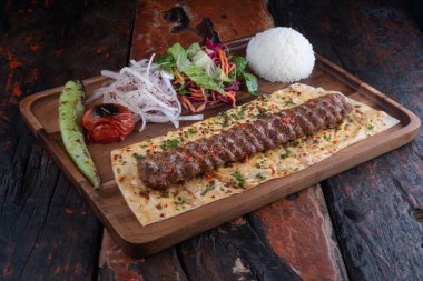 Kırsal ahşap masaya izole edilmiş pirinç ve sebzeli Türk lula kuzusu veya biftek kebabı 