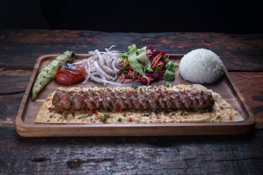 Kırsal ahşap masaya izole edilmiş pirinç ve sebzeli Türk lula kuzusu veya biftek kebabı 