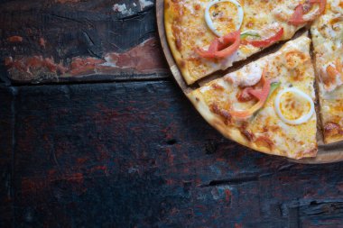 Deniz ürünleri, domates, paprika ve ahşap arka planda izole edilmiş mozzarella peynirli taze lezzetli pizzanın yakın görüntüsü.