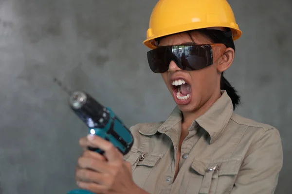 有吸引力的年轻女建筑工人的画像 整体上有钻头 头盔和防护眼镜与混凝土墙背景隔离 — 图库照片