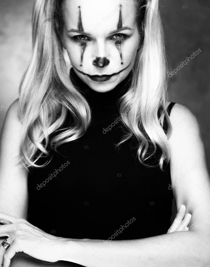 Halloween clown woman portrait posing over concrete wall background - black and white photo