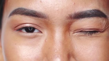 Beyaz arka planda kesilmiş kadın portresi. Aşırı yakın plan. Kapalı çekim kadın gözlerini kapatıyor ve açıyor - video yavaş çekim