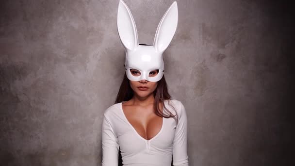 白いドレスとウサギのマスクで美しいいちゃつくアジアの女性の肖像画は 遊び心のあるカメラのためにポーズをとっています ビデオでスローモーション — ストック動画