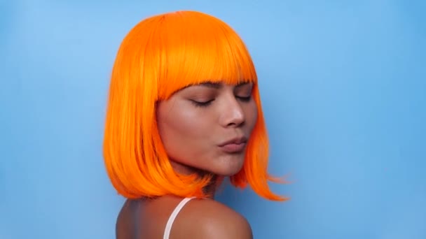穿着鲜艳橙色假发 身披蓝色背景的美丽而快乐的亚洲女人的画像 — 图库视频影像