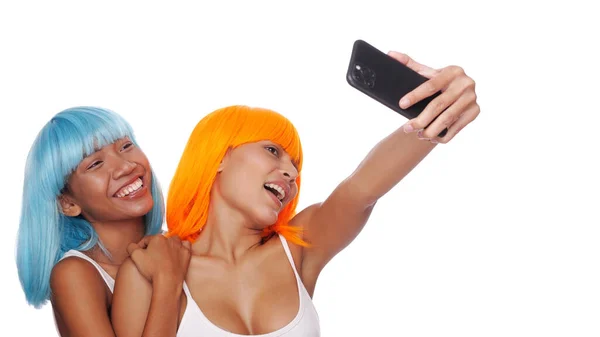 2つの美しい幸せなアジアの女性の友人の肖像画で明るい青とオレンジのウィッグは白い背景にスマートフォンで自撮り写真をやって — ストック写真