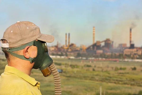 Person i gasmask och mössa på industriell rökning pipe bakgrund — Stockfoto