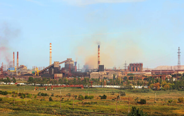 Вид на крупный промышленный завод с дымящимся фактором
