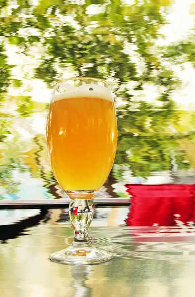 Vidro de cerveja espumoso na mesa e fundo embaçado . — Fotografia de Stock