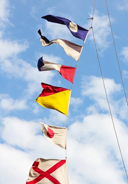 Námořní signální vlajky na stěžni proti zatažené obloze. — Stock fotografie