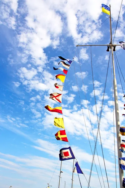 Uppsättning marina signalflaggor på en mast mot molnig himmel. — Stockfoto