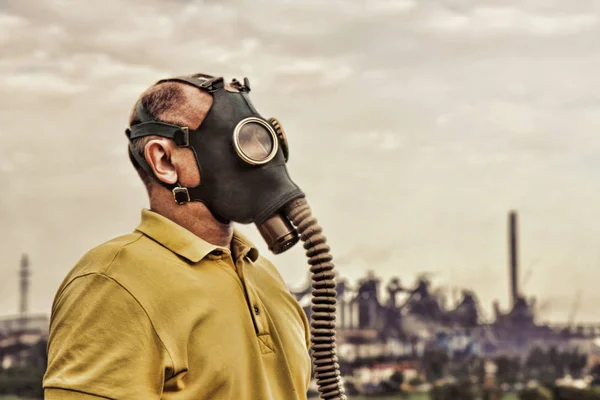 Man wearing gas mask standing against of industrial factory. — Stock Photo, Image