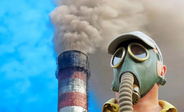 Osoba v plynové masce na průmyslovém kouřícím potrubí pozadí. — Stock fotografie