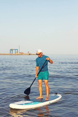 Sörf tahtası. Gençler güneşli bir günde yaz denizinde SUP sörf tahtasında antrenman yapıyor..