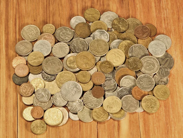 Various coins of world on wooden background taken closeup.