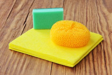 Ev kavramı. Tahta zeminde temizlik süngeri, fırça fırçası ve sarı mikro fiber bez..