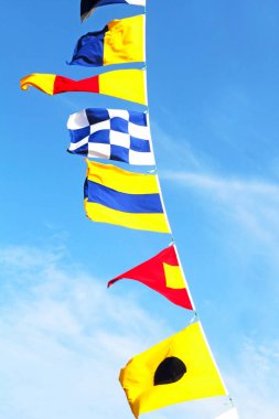 Bulutlu mavi gökyüzü arkaplanındaki deniz sinyal bayrakları yakından çekildi.