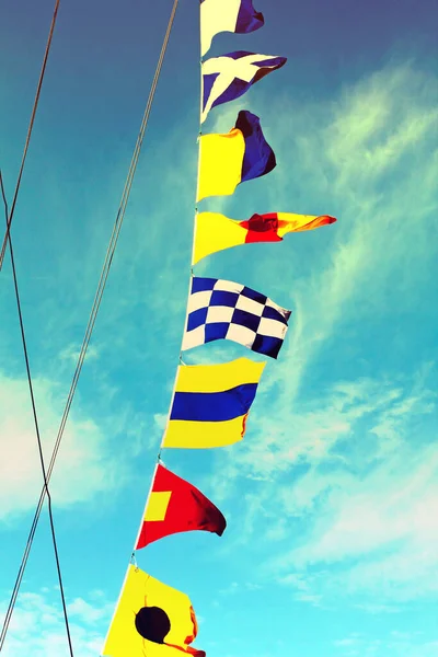 青い曇り空に対して帆走マストに設置された海の信号旗がクローズアップされました トーン画像 — ストック写真
