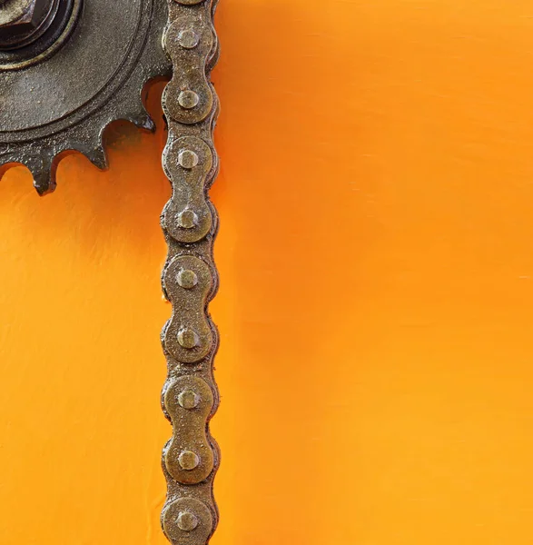 黒金属歯車とテキストのための空のスペースとオレンジの背景にチェーン — ストック写真