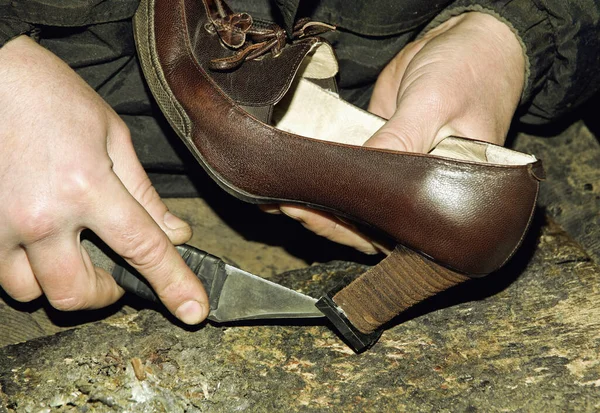 Shoemaker is repairing leather shoe taken closeup.Toned image.