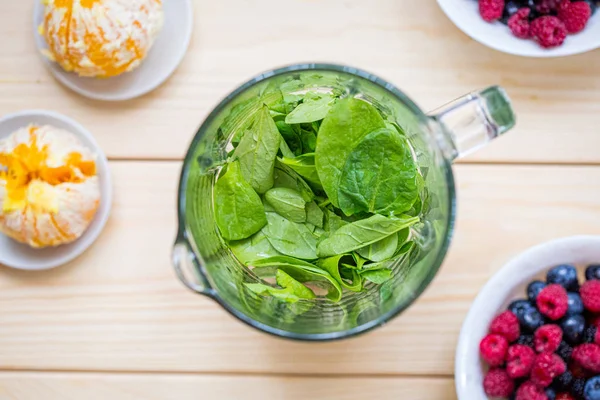 Bacche miste con spinaci e arancia in un frullatore, frullato pre — Foto Stock