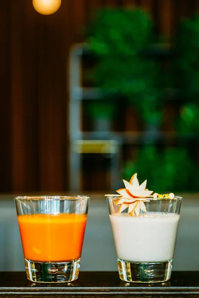 Два бокала смузи (морковь и апельсин, яблоко и кокосовый орех) i Лицензионные Стоковые Фото