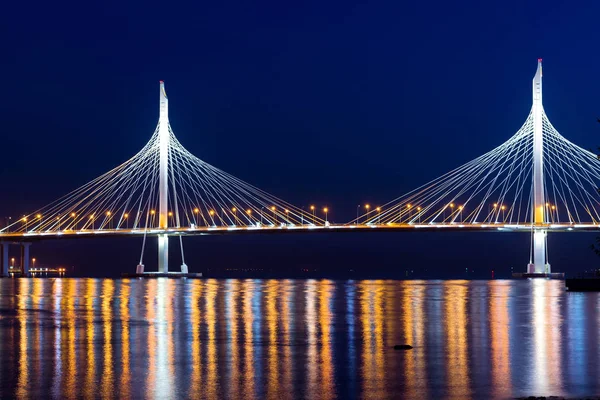 Cable-stayed bridge connects the roads of Western high-speed diameter in St. Petersburg, Russia. Night lighting of bridge is reflected in water of Peter\'s fairway. Modern industrial road structures