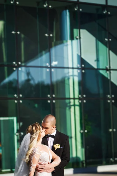 Gelin ve damat tutarak ve yakınındaki futuristik binada öpüşme — Stok fotoğraf