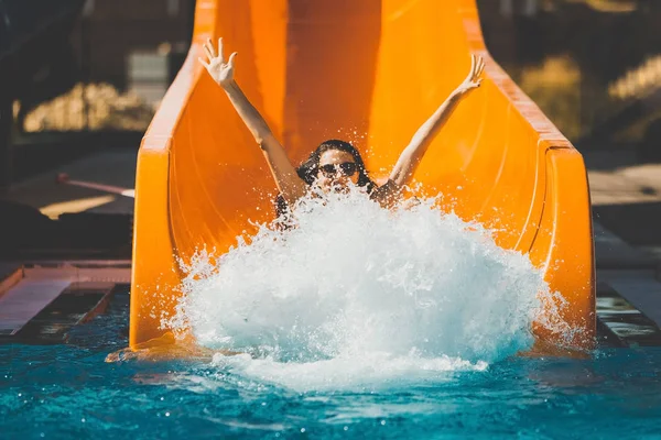 joyful woman going down by the slide in aqua park