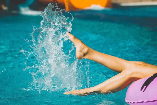 Damenbeine spielen mit Wasser im Pool — Stockfoto