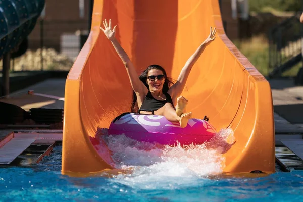 Femme heureuse descendant par la glissière dans le parc aquatique — Photo