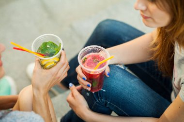 iki kız konuşmak ve soğuk kokteyl, güzel arkadaşlar içmek, şehir ve içecek limonata güzel kız yürümek. portre kadar kapatın