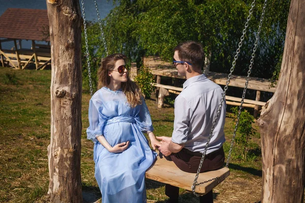 Junges schwangere Mädchen reitet auf Schaukel mit Mann im Freien — Stockfoto