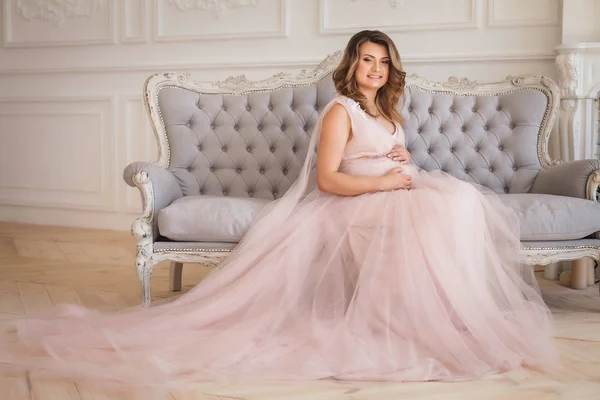 Young pregnant girl sitting on sofa — Stock Photo, Image