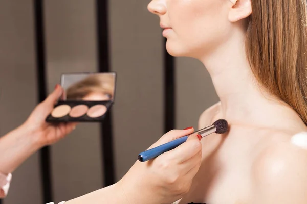 Artista de maquiagem aplicando um corretor em uma clavícula de um modelo — Fotografia de Stock