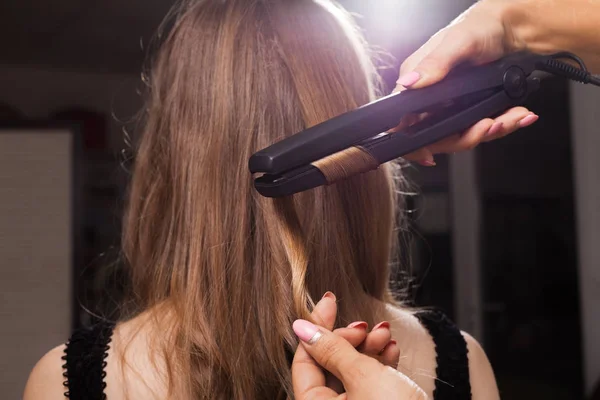 Hairdresser curling a hair strand of a woman — Stock Photo, Image
