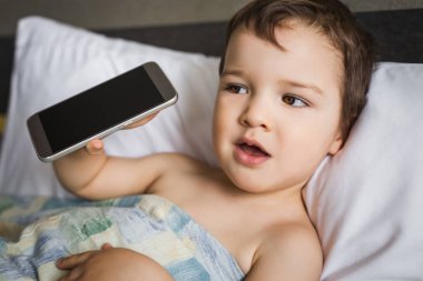 küçük boy gösteren cep telefonu sabah yatakta yatıyordu holding