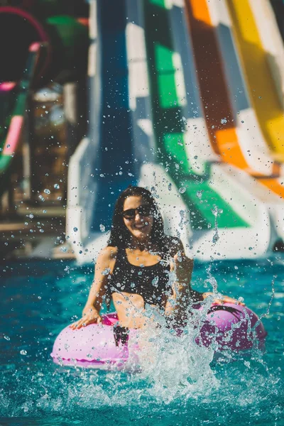 Lächelnde Frau im Bikini sitzt im Pool auf Gummiring — Stockfoto