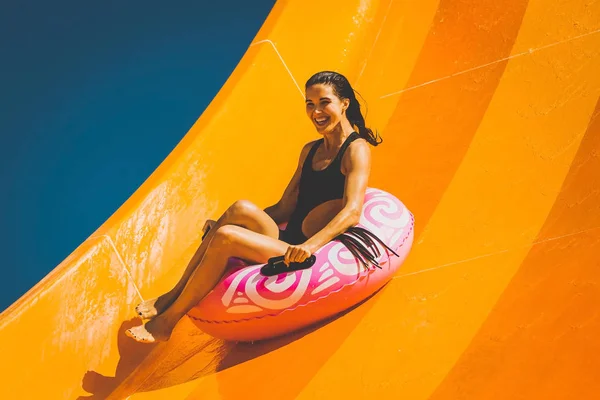 Femme brune s'amuser sur la glissière d'eau dans un parc aquatique — Photo