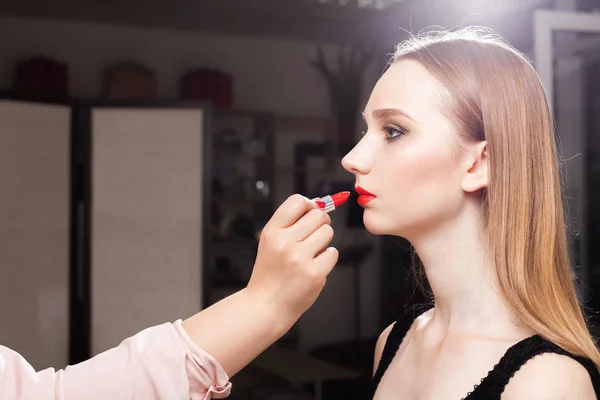 Makeup woman putting red lip gloss on a client — Stock Photo, Image