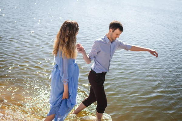 Man och gravida hustru vandrande på vatten floden stranden. hålla händerna tillsammans — Stockfoto