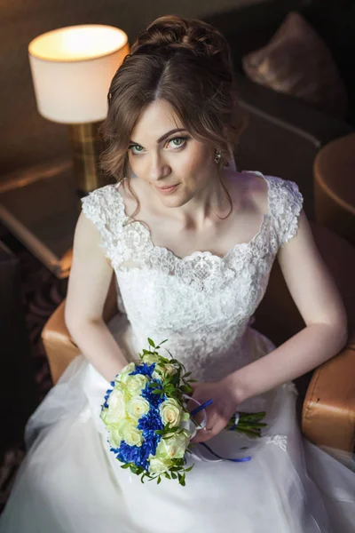 Невеста с цветами сидит на стуле в комнате — стоковое фото