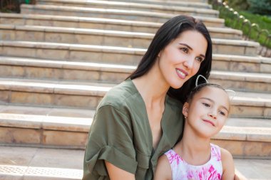 Güzel anne ve doğada merdivenlerde oturan kızı