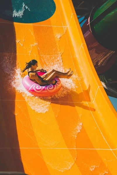 Ragazza si diverte sullo scivolo d'acqua arancione nel parco acquatico — Foto Stock