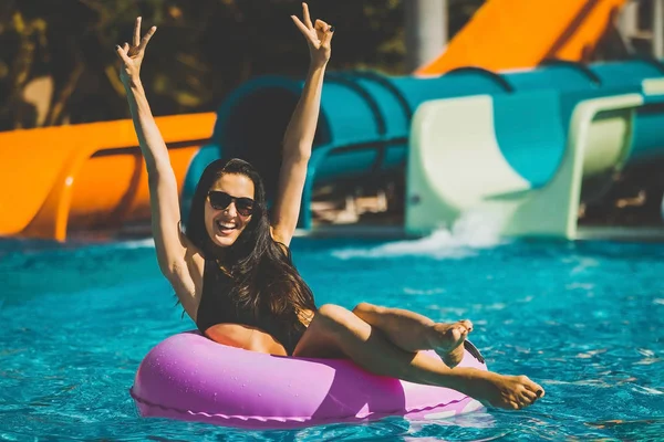 Glückliche hübsche Frau auf Schwimmring im Schwimmbad — Stockfoto