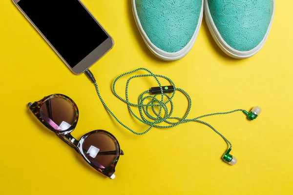 Solglasögon, hörlurar, skor och en smartphone — Stockfoto
