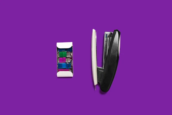 Black stapler with box of braces on a purple surface — Stock Photo, Image
