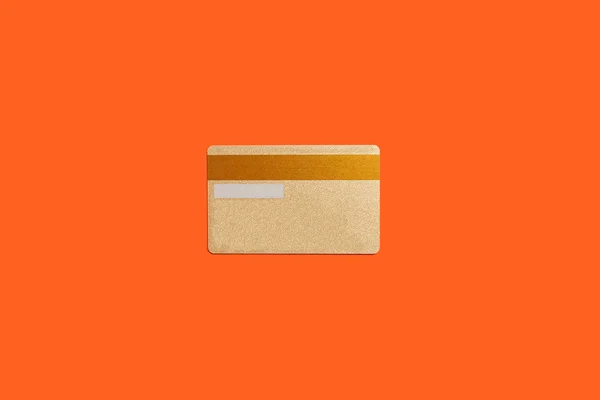 Gold kreditkort isolerat på den orange bakgrunden — Stockfoto